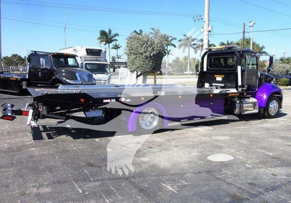 Peterbilt tow truck with flatbed, truck cabin on right, long flatbed, company watermark center.