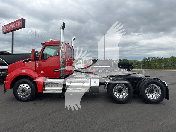 Red 2026 Kenworth T880 conventional daycab truck side view showing chrome fuel tanks, exhaust stacks, and dual rear axles.