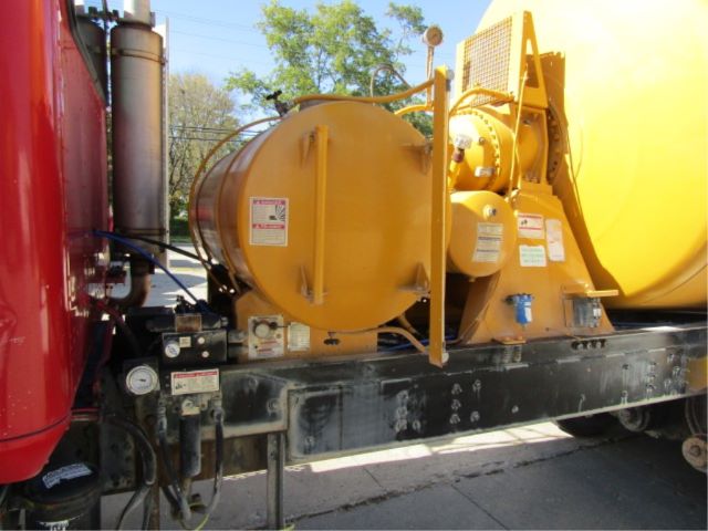 Package with a large yellow circular hose reel and pump mounted on a chassis, with control panels and labels on the equipment.