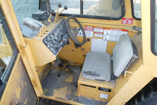 Cab interior of a Grove YB4410 crane showing operator seat, steering wheel, and control panel with gauges and levers.