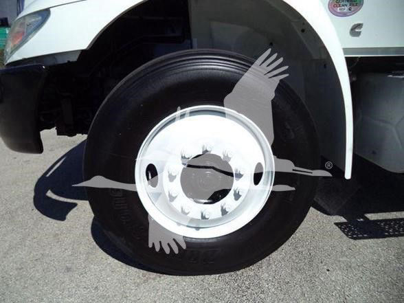 Truck front wheel with white rim and black tire in the wheel well of a white International DURASTAR 4300.