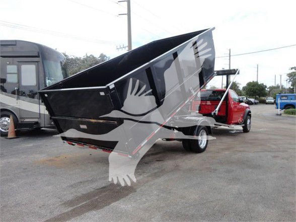 Dodge Ram 5500 SLT hooklift truck with a raised black dump bed and red cab; residential/lot setting in background.