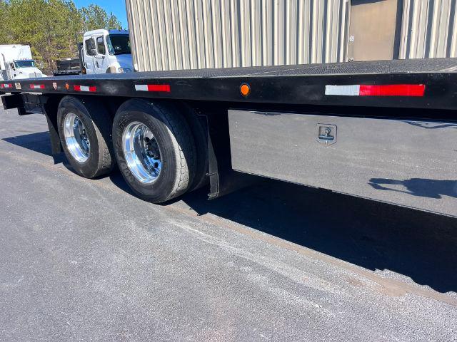 Peterbilt 348 rollback truck with dual rear wheels and flatbed, side storage box visible, outdoor lot.