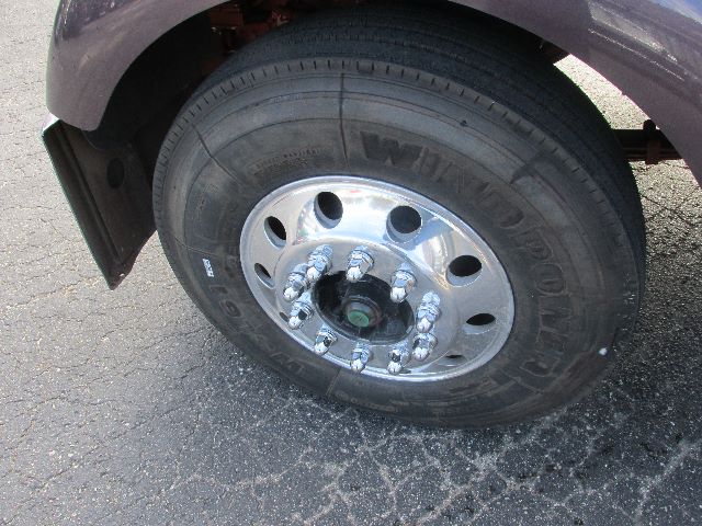 Wheel and tire of a Kenworth W900 showing steel wheel with lug nuts and tire tread.