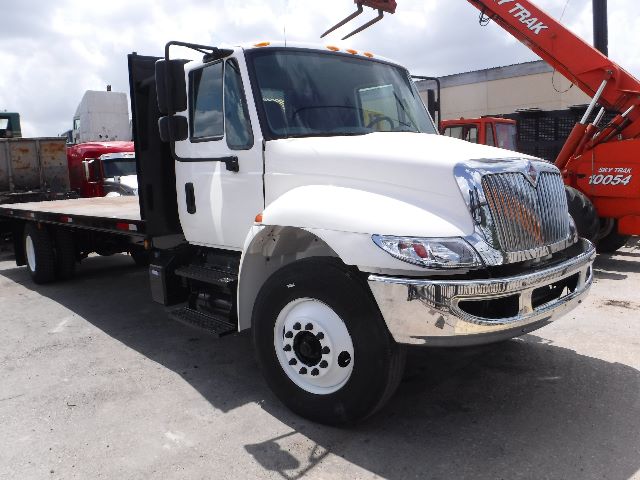 Flatbed truck showing white 2018 International 4300 cab and chrome grille with dual headlights.