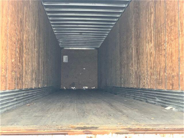 Interior of a 2013 Stoughton dry van trailer showing wooden side walls and metal floor with a small vent opening toward the rear.