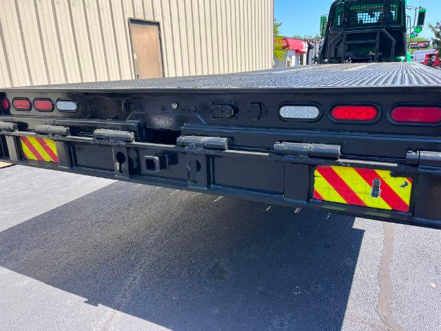 Back of a black rollback truck bed with safety lights and reflective chevrons. visible components include mounting brackets, rear frame, and hinge mechanisms.