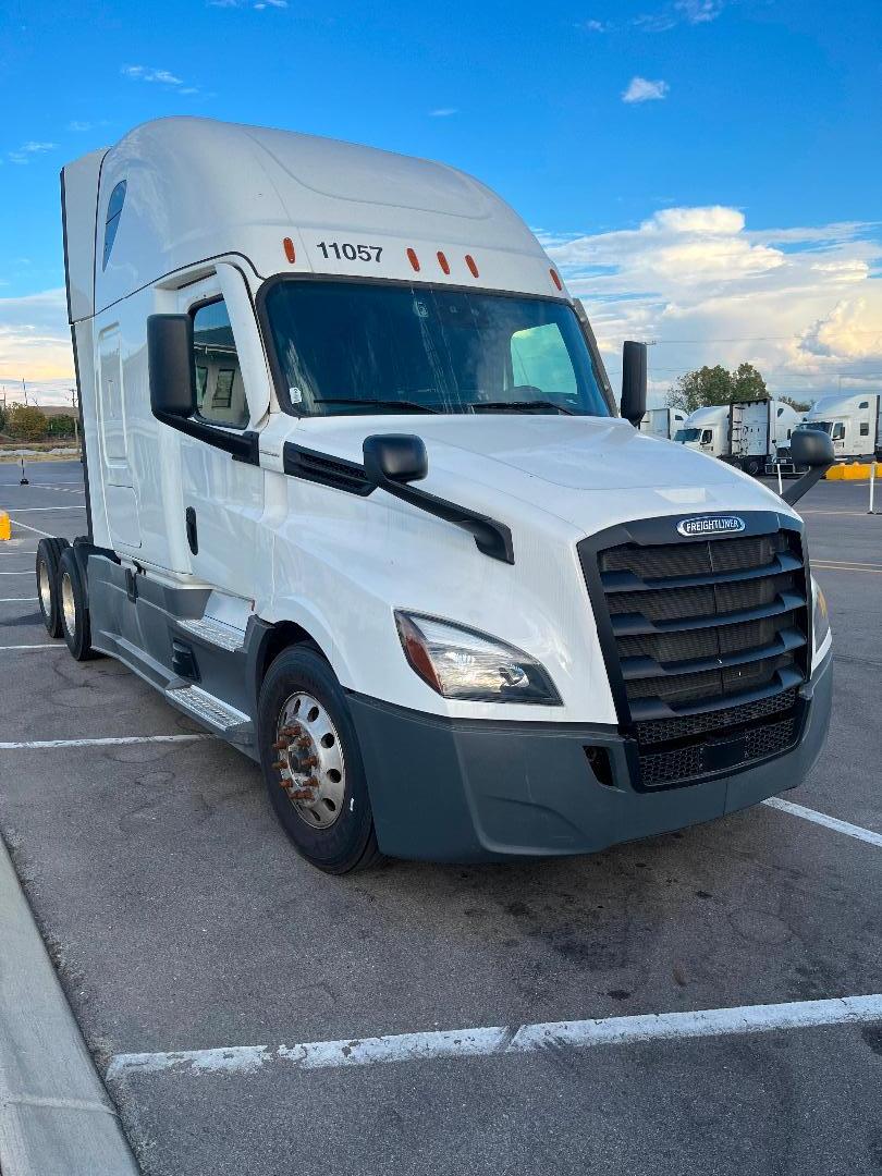 Freightliner Cascadia 126 white semi-truck in a parking lot, front-left view with black grille and headlights.