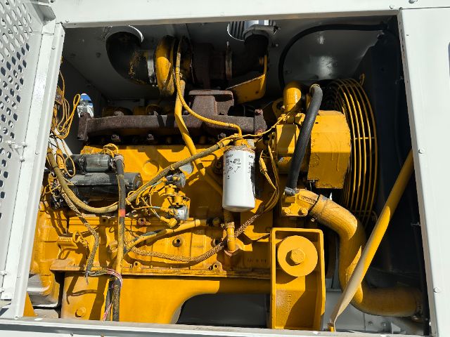 Yellow International diesel engine with exposed components in a vacuum truck bay, showing hoses, filters, and belt-driven machinery.