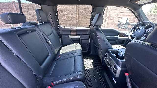 Interior of a 2022 Ford F-550 Lariat cab showing rear bench seat, front seats, center console, and dashboard with leather upholstery and cup holders.