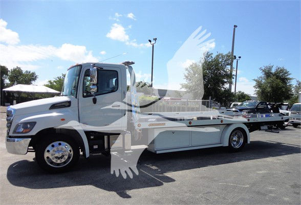 2022 Hino 268A tow truck in a parking lot, side view showing flatbed with storage compartments.