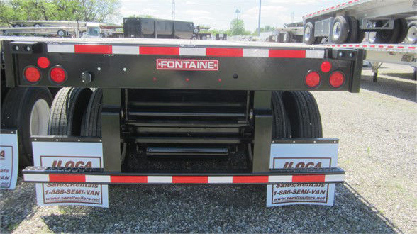  Fontaine flatbed trailer rear view showing extendable steel bed and taillights, Fontaine logo, mud flaps, and reflective safety stripe.
