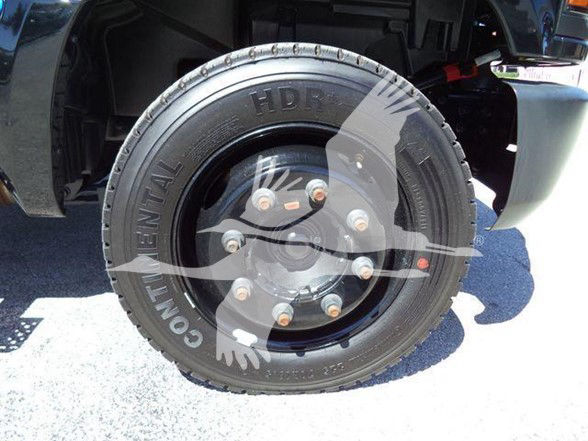 Vehicle wheel and tire on Chevrolet Silverado 6500HD flatbed showing Goodyear Commercial HD tire and alloy wheel with lug nuts.