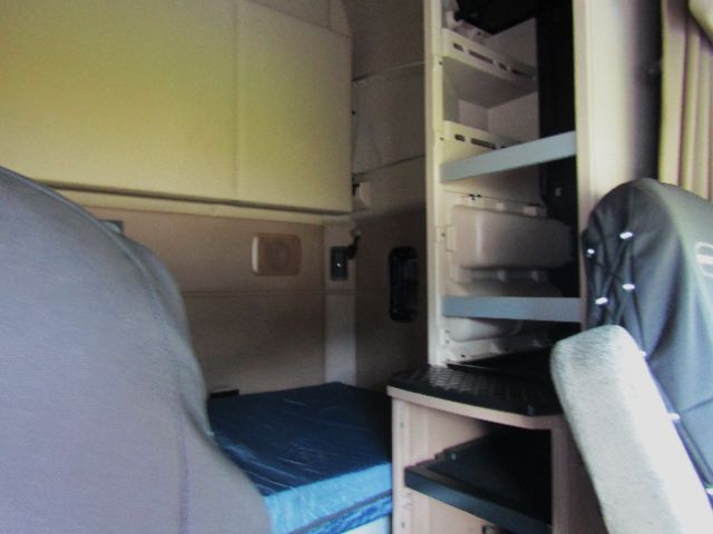 Kenworth truck cab interior showing sleeper bunk and storage shelves.