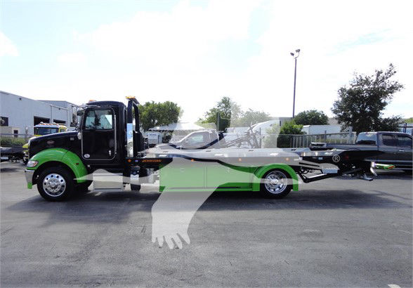 Peterbilt 337 tow truck in green and black, side view with long wheelbase and car carrier bed.