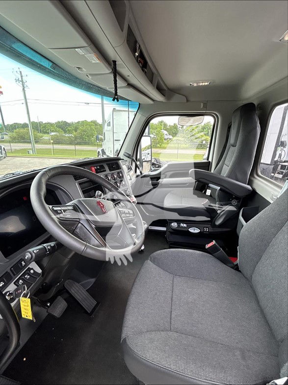 Kenworth T880 truck cab interior showing steering wheel, dashboard, and driver seat from the passenger side, with controls and gear area visible.