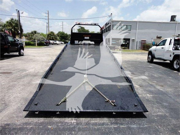 Isuzu NRR tow truck flatbed with ramps and safety chains in foreground.