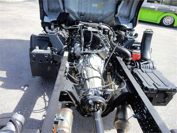 Isuzu NPR HD truck chassis viewed from rear with exposed engine and transmission, various hoses and wiring, front cab removed