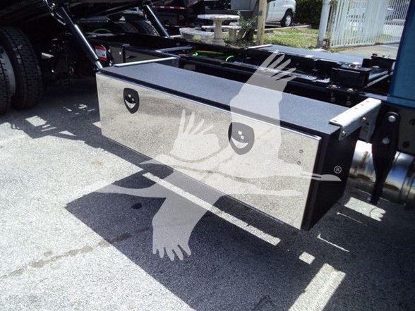 Tractor-trailer storage toolbox mounted under the chassis with a gray metal toolbox and side rails visible.