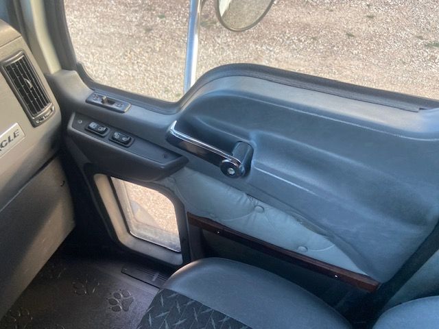 Truck cab interior door panel showing window controls and armrest, with blue fabric and chrome accents.
