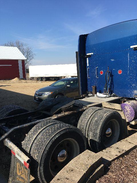 Kenworth W900L truck chassis with blue sleeper cab, dual rear axles, and large wheels.