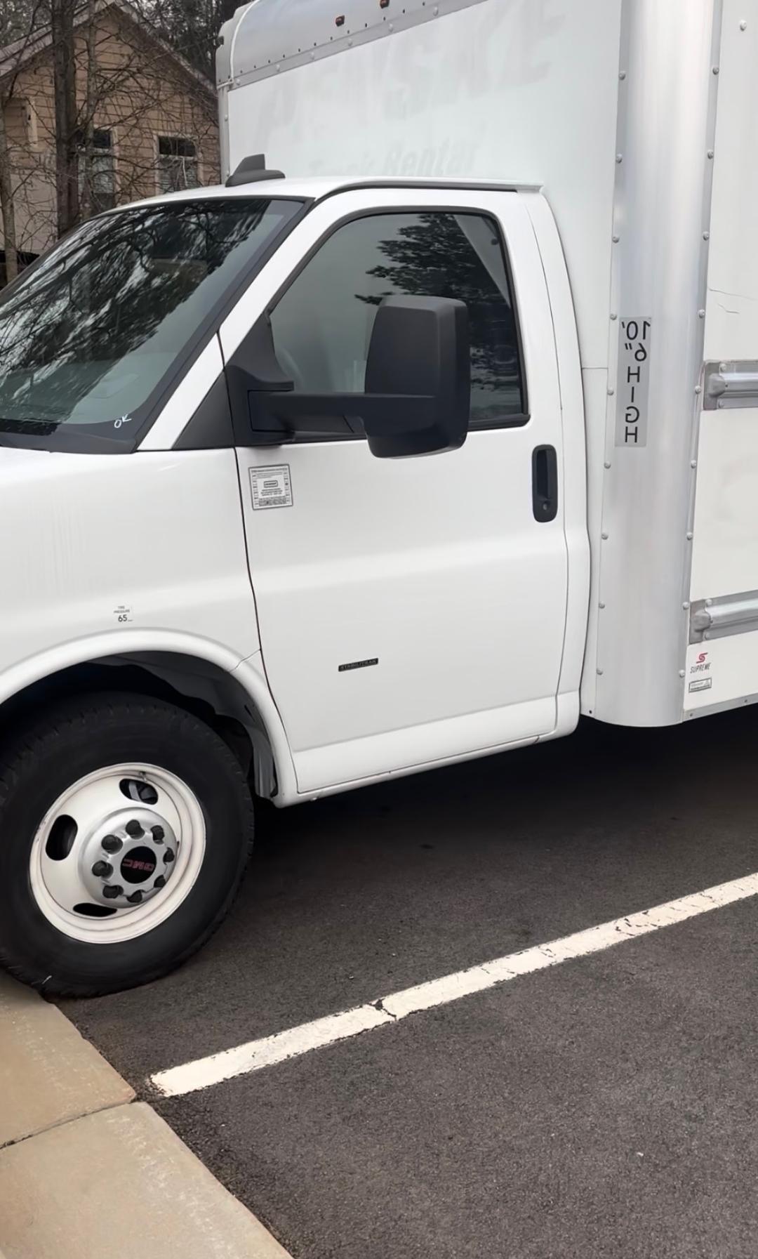 GMC Savana 3500 cargo van side profile showing white cab, black side mirror, and box up to door; front wheel visible; Vin sticker area on door.