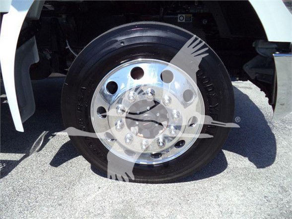 Wheel and tire assembly of a Kenworth truck with chrome hubcap and black tire; wheel well and fender visible.