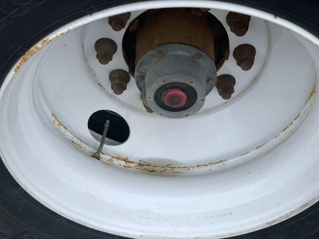Manac trailer wheel hub showing white steel rim with rust around edges and red center cap.