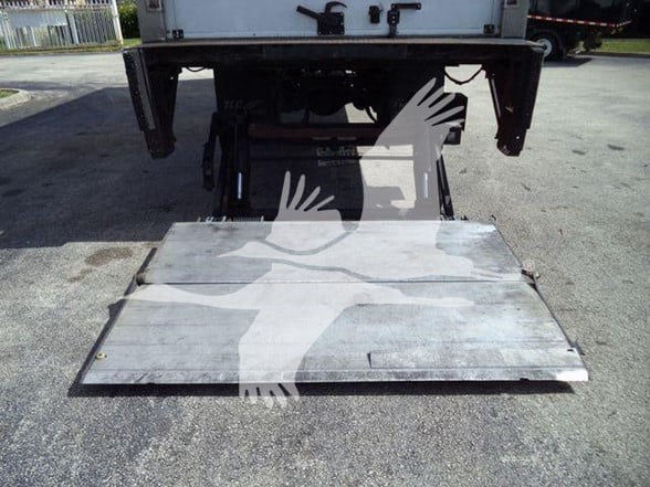 Rear of a reefer truck with a lowered ramp/platform and two hydraulic arms visible underneath. No legible text on the ramp itself.