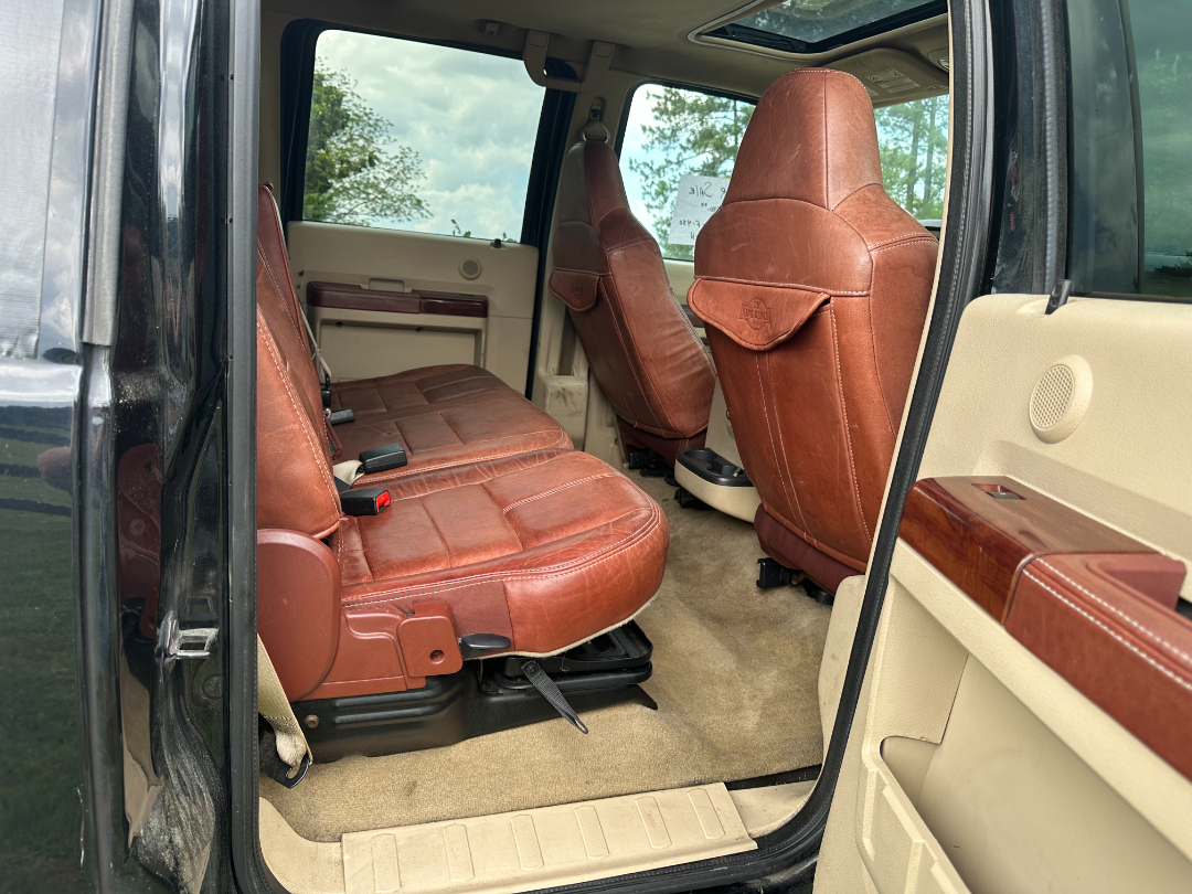 Ford F-450 King Ranch interior showing red leather seats in front and rear, beige door panel, and tan carpet.