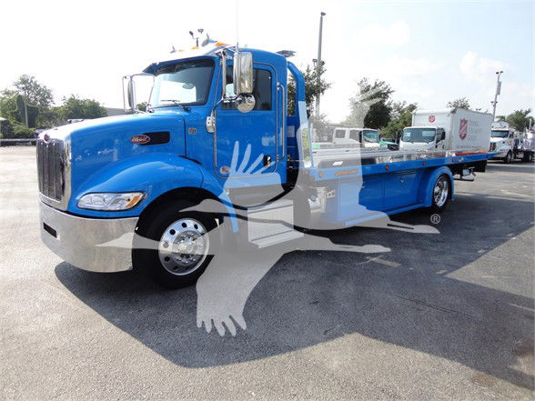 Blue 2022 Peterbilt 337 tow truck in a dealership lot with flatbed and chrome bumpers.