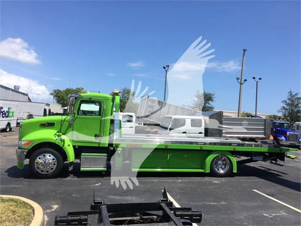Green Peterbilt 337 tow truck side view showing flatbed and chrome wheels.
