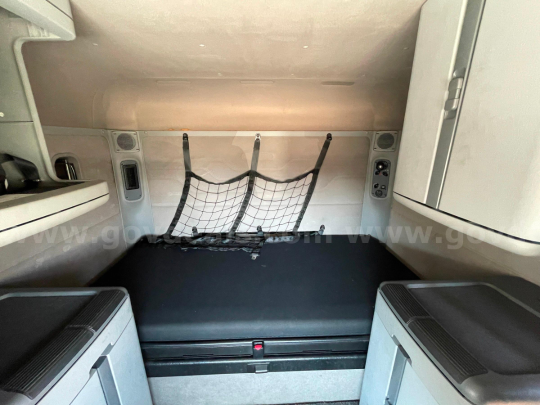 Cab interior showing sleeping area with netted storage straps and side panels in a Freightliner truck cabin.