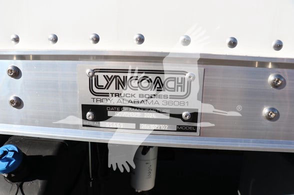 Lyncoach truck bodies plate mounted on a box truck with bolts and aluminum finish.