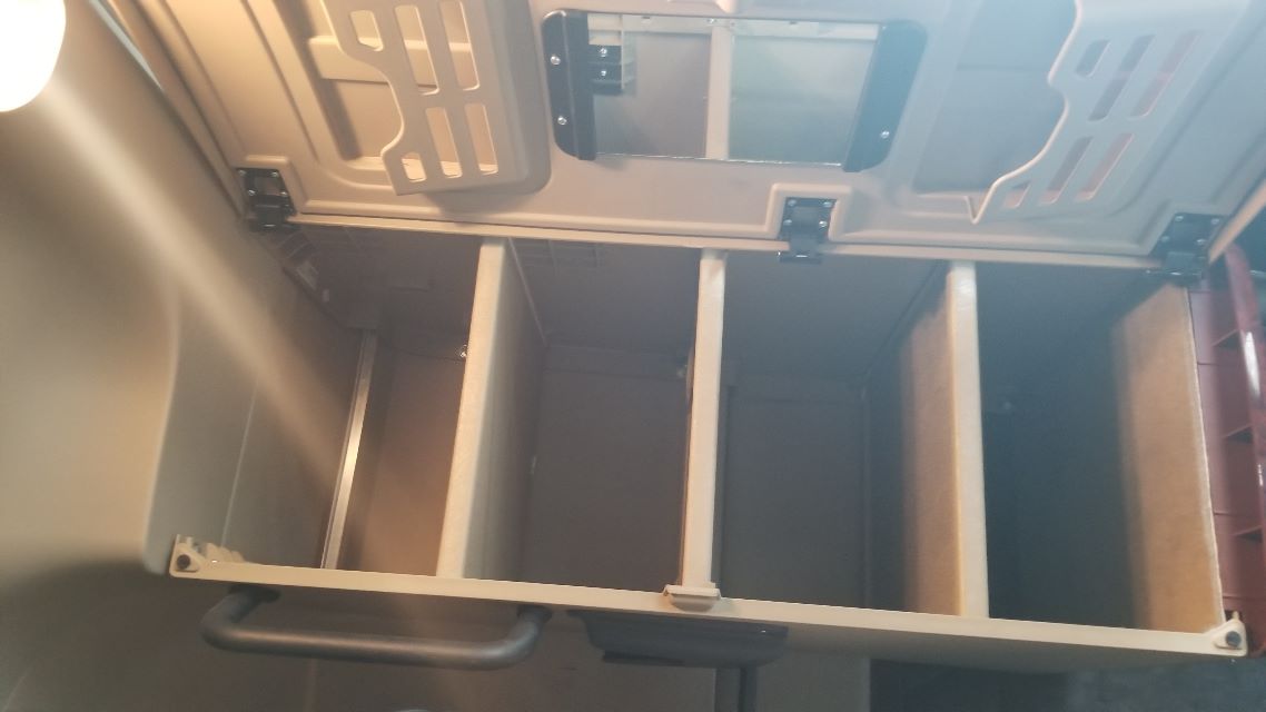 Cabinet in truck cab with open shelving inside, three metal shelves and interior cabin paneling.