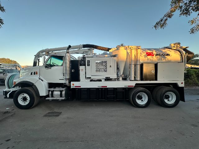 Vacuum truck on a white 2006 Sterling L8500 with Vactor/Vaccon tank and hoses, side view showing engine bay area and rear vacuum tank.