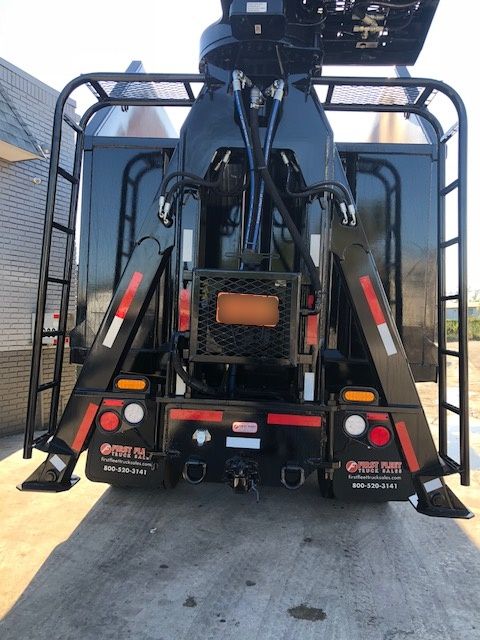 Back view of a 2018 Peterbilt 567 grapple trucks with hydraulic arms, rear bumper, taillights, and protective frame.