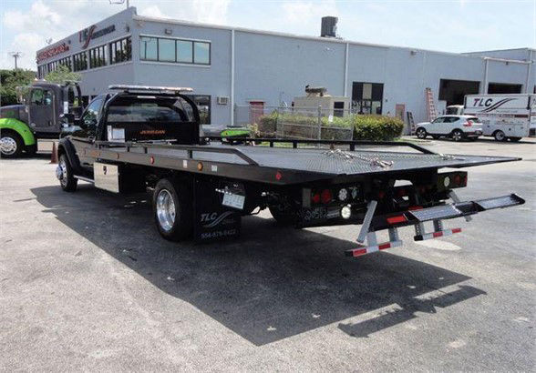 Ram 5500 tow truck flatbed with extended ramp, rear view showing flatbed and wheel chocks.
