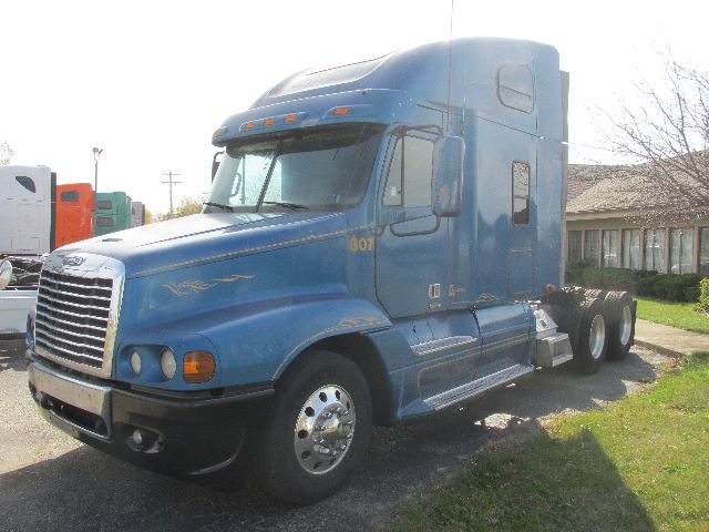 Freightliner Century conventional sleeper semi-truck in blue, angled front view showing cab, grille, and dual rear axles.