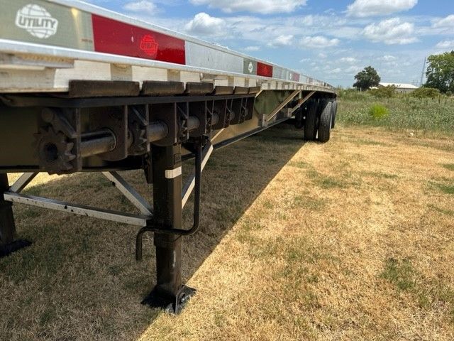 Utility flatbed trailer with landing gear and dual rear wheels, 48x102 dimensions, side rails with reflective tape.