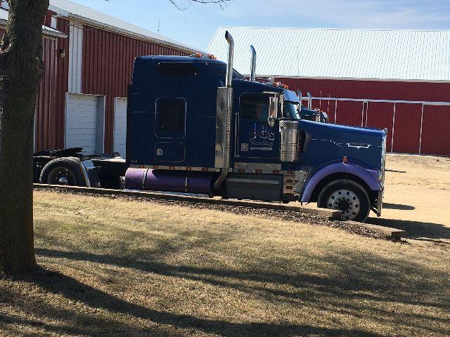Kenworth W900L tractor cab in blue with sleeper, side view showing exhaust stacks and purple fuel tank