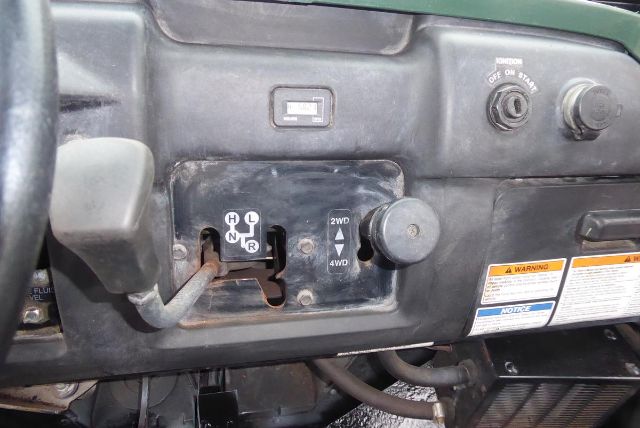Truck dashboard showing gear lever with H N L R positions and 2WD/4WD switch; warning labels and controls visible.