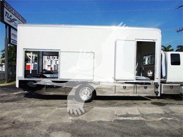 Truck body of a 2022 International MV Tow truck showing side service doors and cabin area, white exterior, with steps and storage compartments along the lower side.