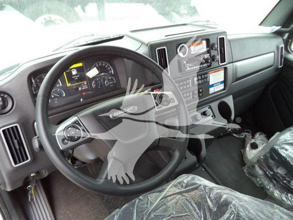 Freightliner Business Class M2 106 cab interior showing steering wheel and dashboard with controls and plastic seat covers.