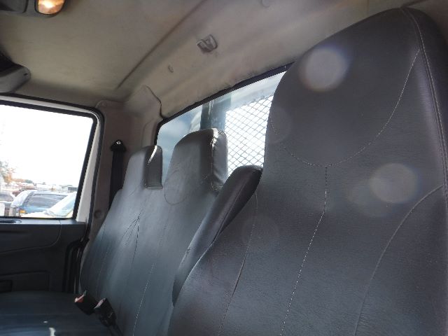 Interior of a 2018 International 4300 flatbed truck cab showing three front seats with black upholstery and seatbelts.