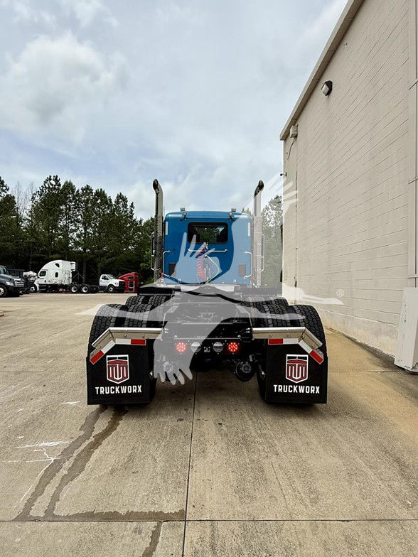 Back view of a blue 2026 Kenworth T880 semi-truck with dual rear axles and mud flaps reading 'TRUCKWORX' and a logo.