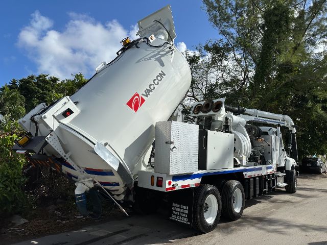 Vacuum truck with a large tilted waste tank labeled VACTON/VACON logo, three-axle tractor with rear hose reels and control boxes