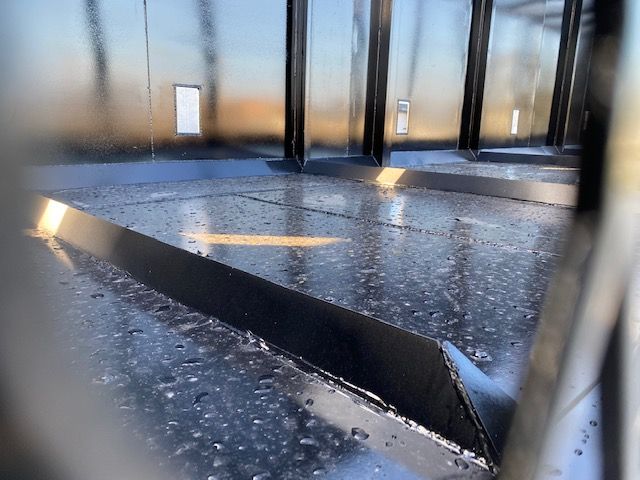 Crush car carrier trailer deck with black metal surface and raised edge, water droplets visible; interior of a 2008 Transcraft 48 ft trailer.