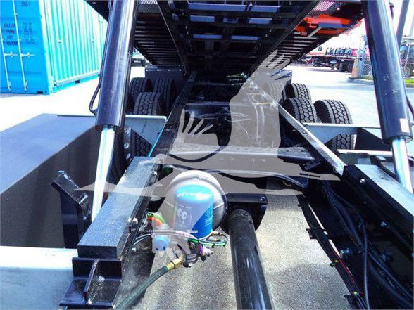 Tow truck chassis with Kenworth T880 show undercarriage and hydraulic components, blue compressor tank visible and framework extending rearward.
