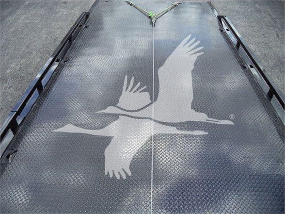 Flatbed truck deck with diamond plate pattern and a large graphic of two flying geese. Center shows a seam and tie-downs. No engine or cab components visible.